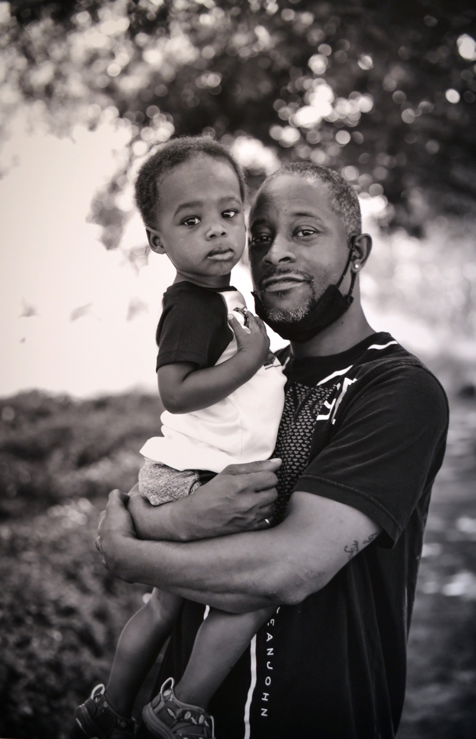 Selected photo from "Dear Black Son" project by Celestia Morgan, Just Injust 2021, Black and White Photograph of black male father embracing young black son