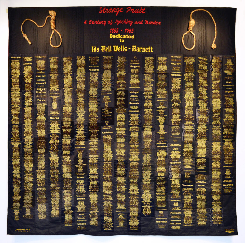 Cropped gallery shot of "Strange Fruit" by April Shipp, Just Injust 2021. Names of lynching victims from1865 to 1965 embroidered in gold on large black quilt with nooses attached to top two corners. 